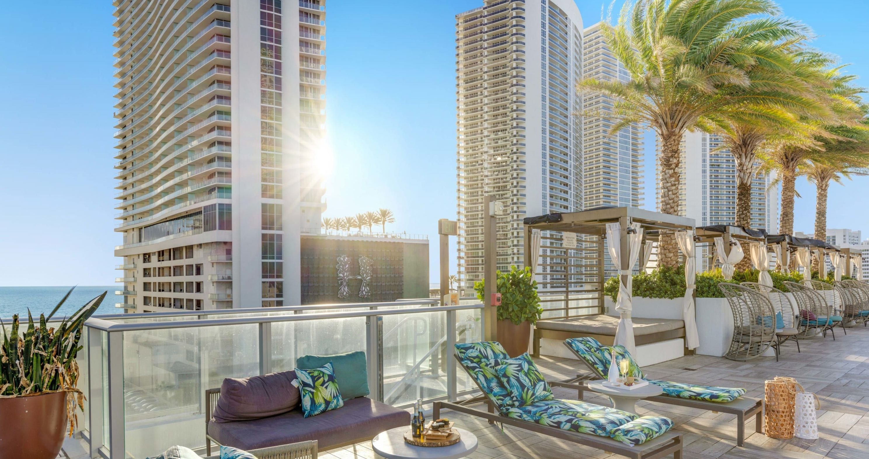 Terraço no telhado com área de estar ao ar livre, vista para o oceano e edifícios altos ao fundo.
