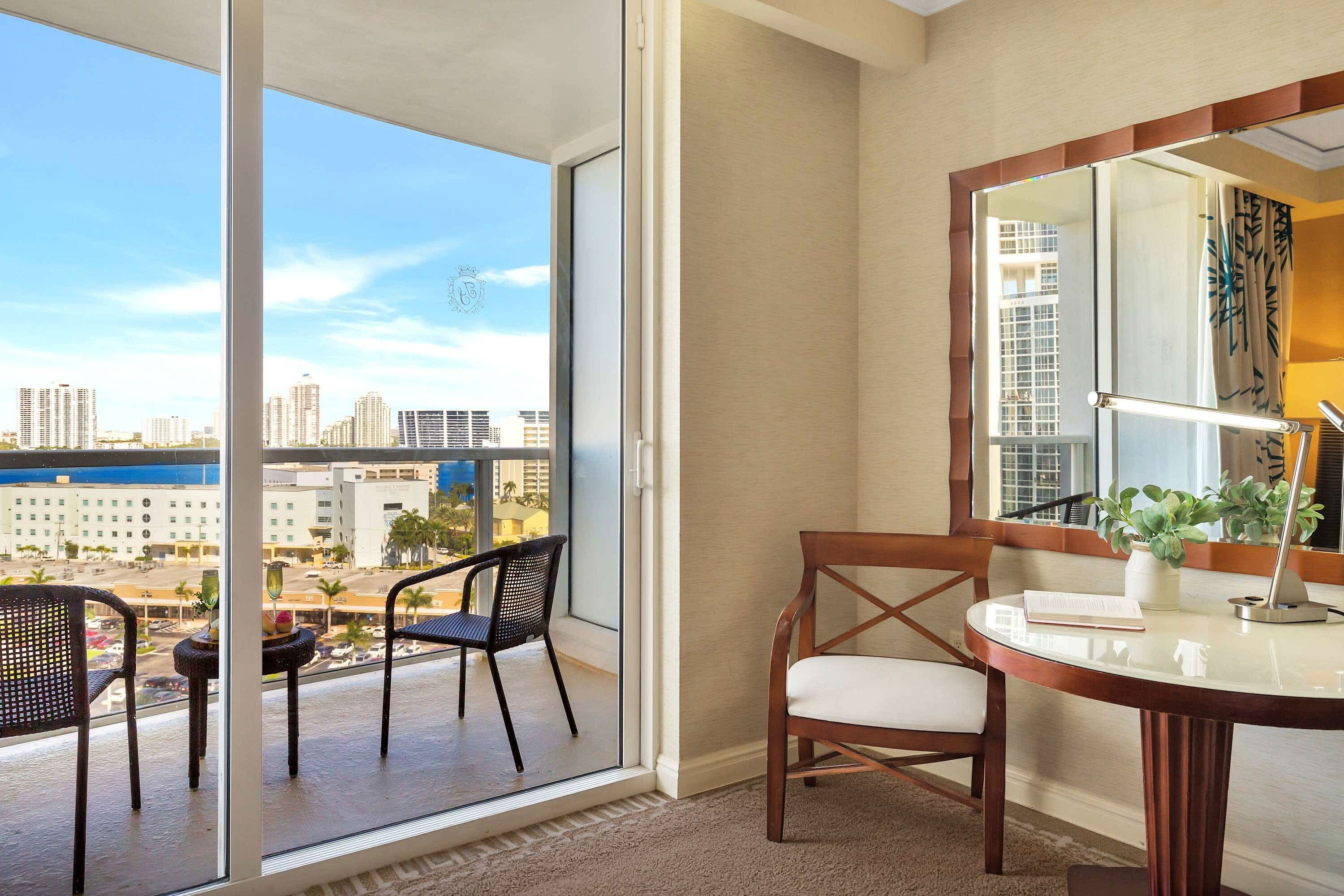 A balcony with a city view, a round table with a chair, and a mirror with a plant.