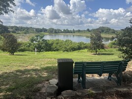 A park with a bench, a small shed, and a lake in the background.