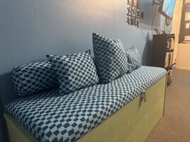 A sofa with a checkered pattern, a wall clock, and a bookshelf in a room.