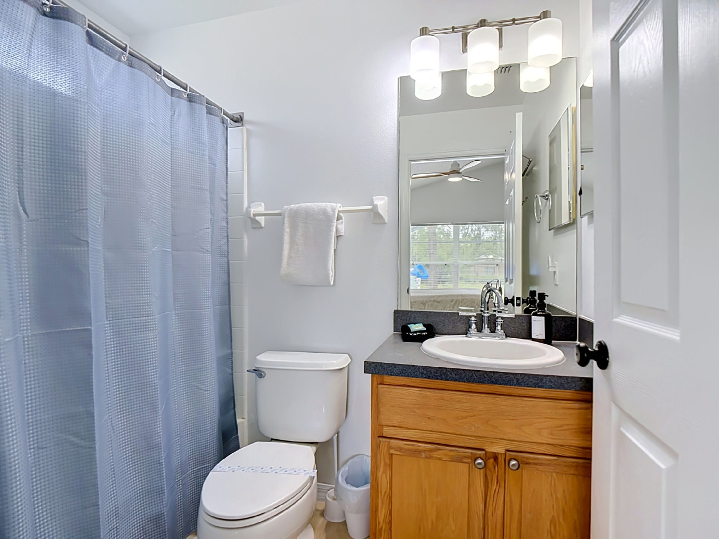 Un bagno con il water, lavandino, specchio e tenda della doccia.