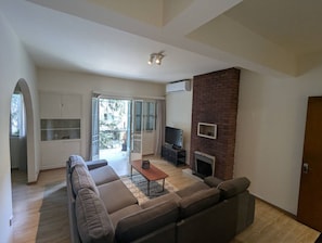 A living room with a sofa, a coffee table, a flat-screen TV, and a fireplace. - Gladstone Apartment in Nicosia (Nicosia)