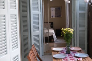 A room with a bed, a table with plates, a vase with flowers, and a painting on the wall. - Gladstone Apartment in Nicosia (Nicosia)