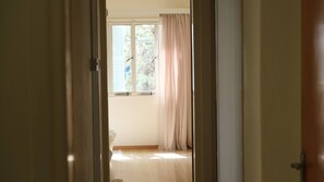 An interior view of a room with a window, curtains, and a door. - Gladstone Apartment in Nicosia (Nicosia)