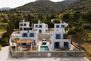 A modern villa complex with a pool, surrounded by lush greenery and hills. - Villa Lara Seafront in Polis (Pachyammos)