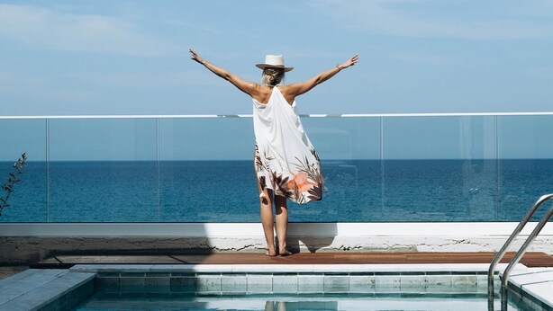 A person standing by a pool with arms outstretched, overlooking the ocean. - Villa Akroyiali Seafront (Pachyammos)