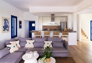 Ein modernes Wohnzimmer mit grauem Sofa, Couchtisch und Küchenbereich mit Bar.
