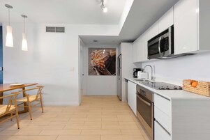 Una cocina moderna con armarios blancos, un microondas de acero inoxidable y un lavavajillas.