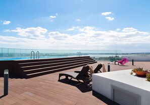 A rooftop terrace with a pool, outdoor seating, and a view of the city. - Althea Luxury Residence (Larnaca)