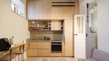 Una cucina compatta con mobili in legno, forno integrato e macchina da caffè.