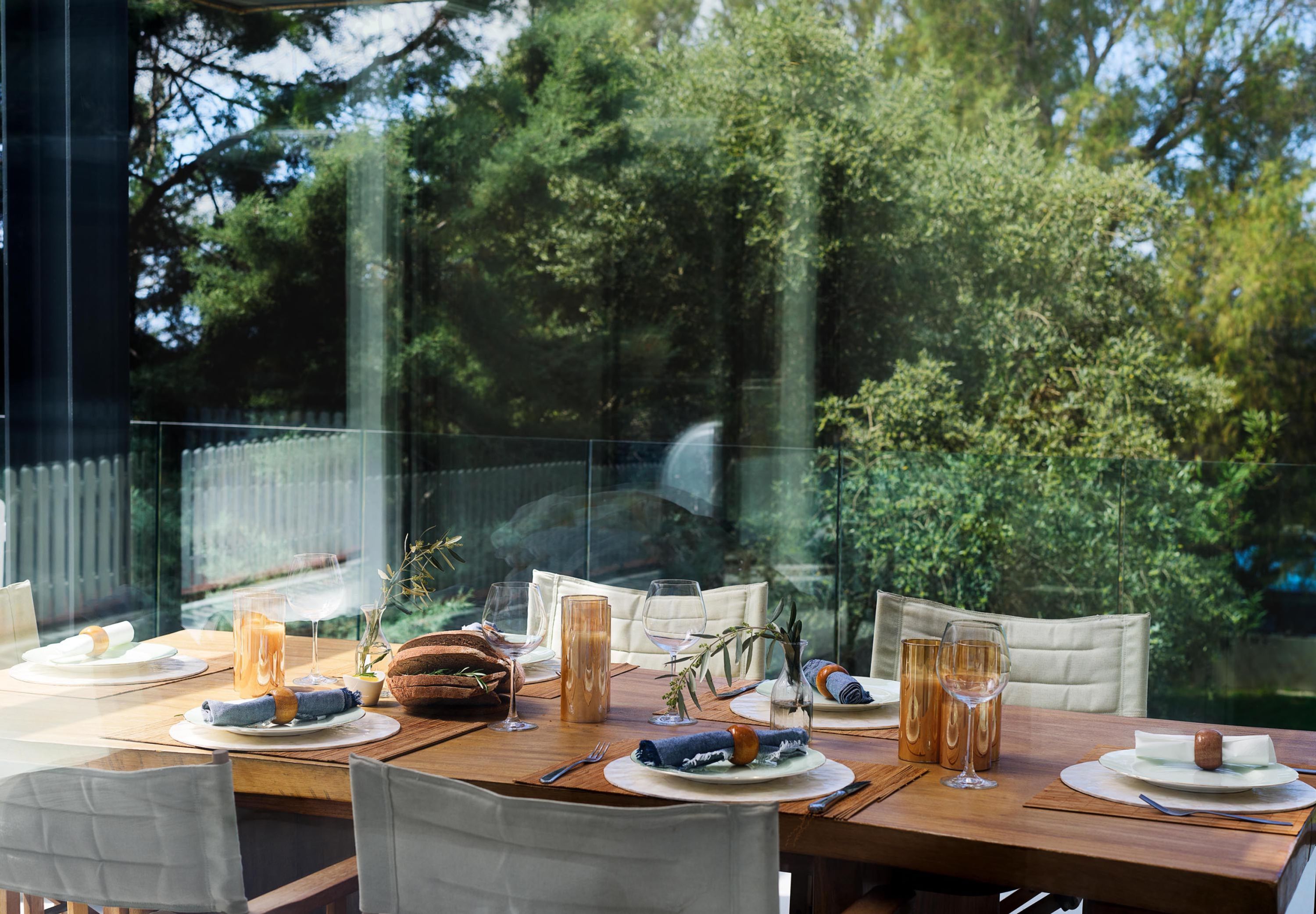 Mesa de comedor para cuatro con vista a un jardín a través de un panel de vidrio.