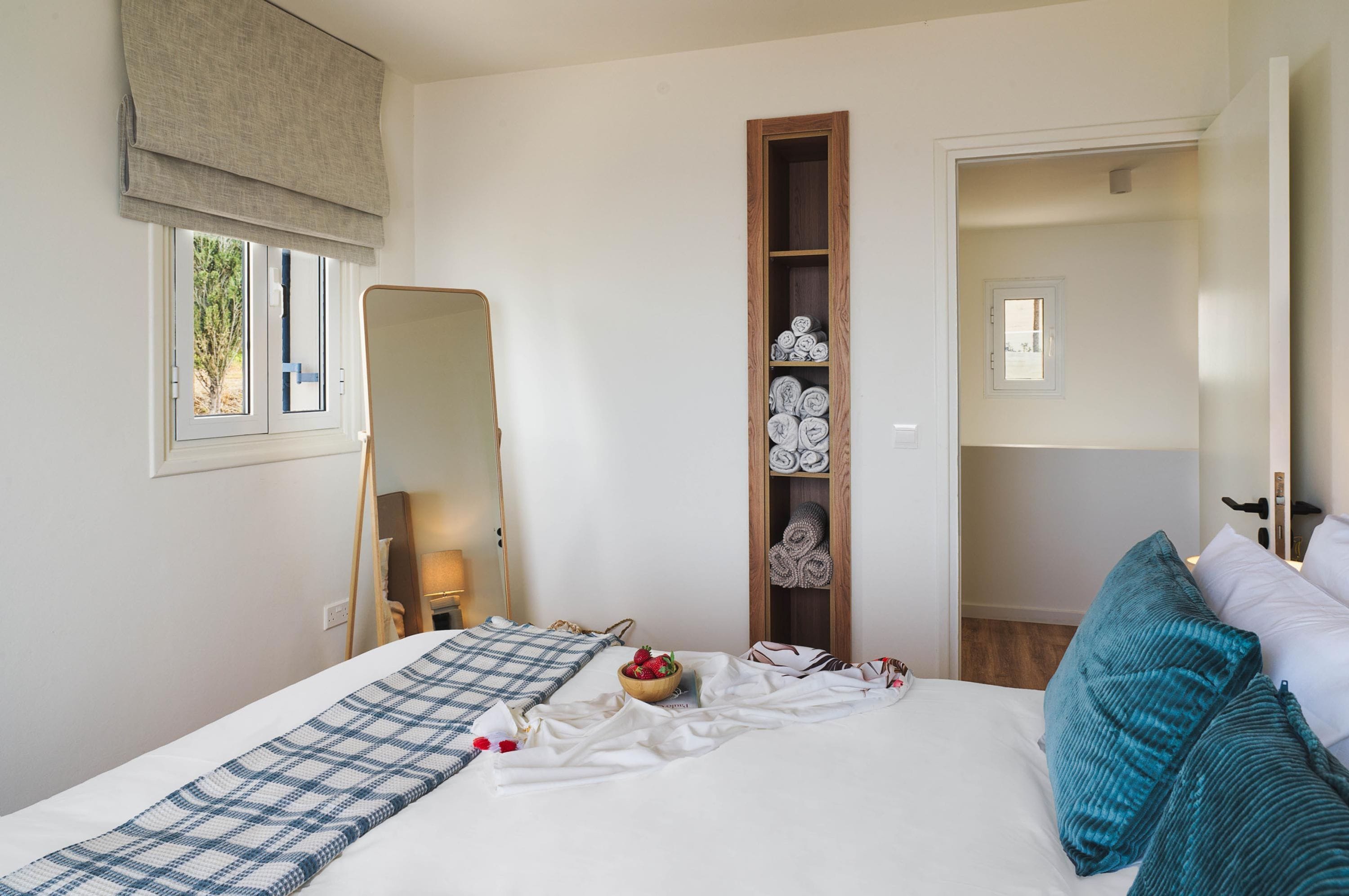 Un dormitorio con cama, espejo, armario y ventana.
