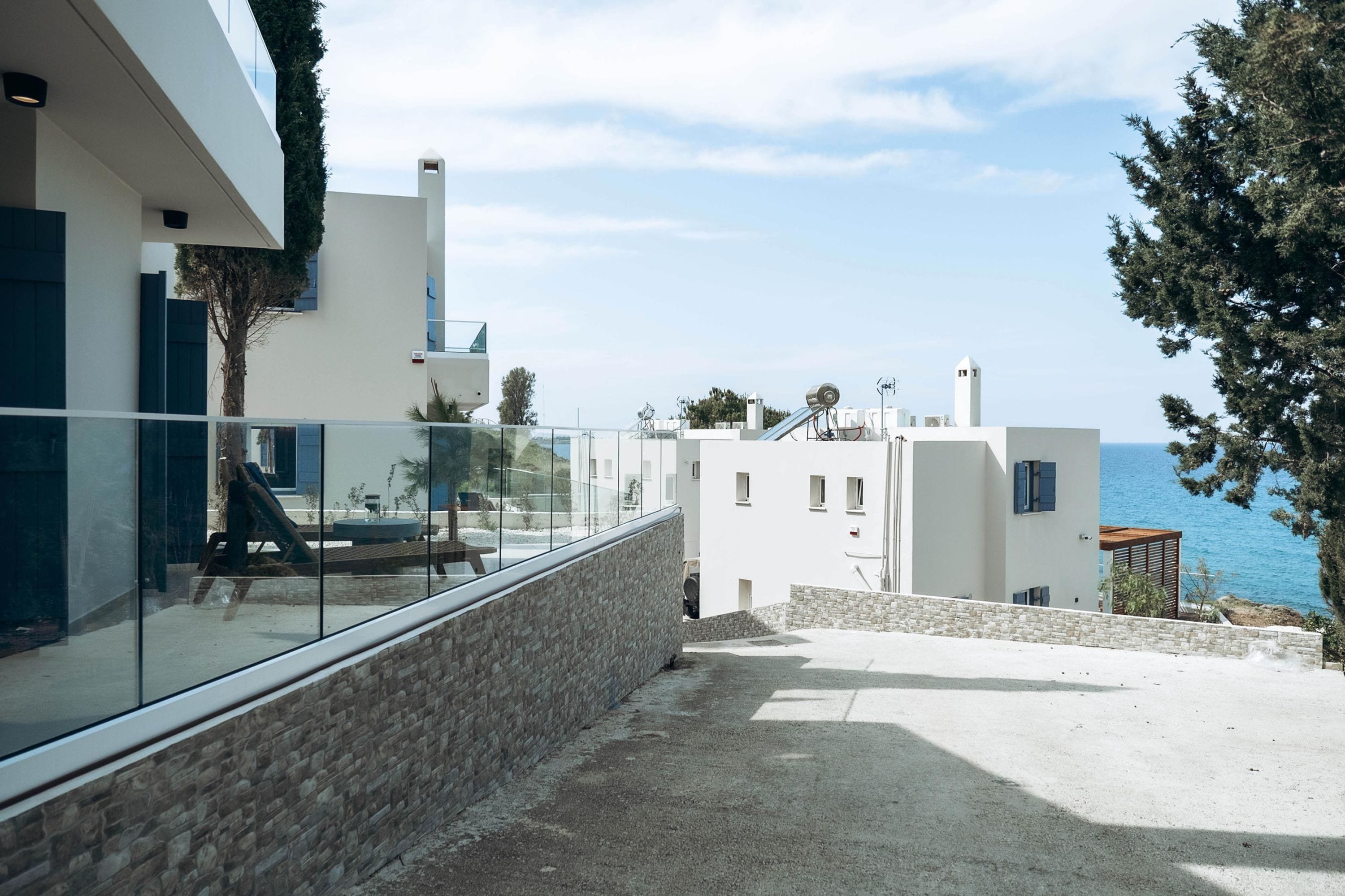 Un edificio moderno con un balcón de vidrio que da a la costa.