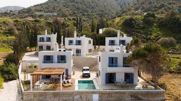 Una villa moderna con piscina, varios niveles y vistas a un paisaje montañoso.