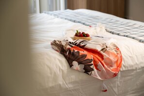 A neatly made bed with a floral-patterned blanket, a bowl of strawberries, and a white pillow. - Villa Omega in Polis (Pachyammos)