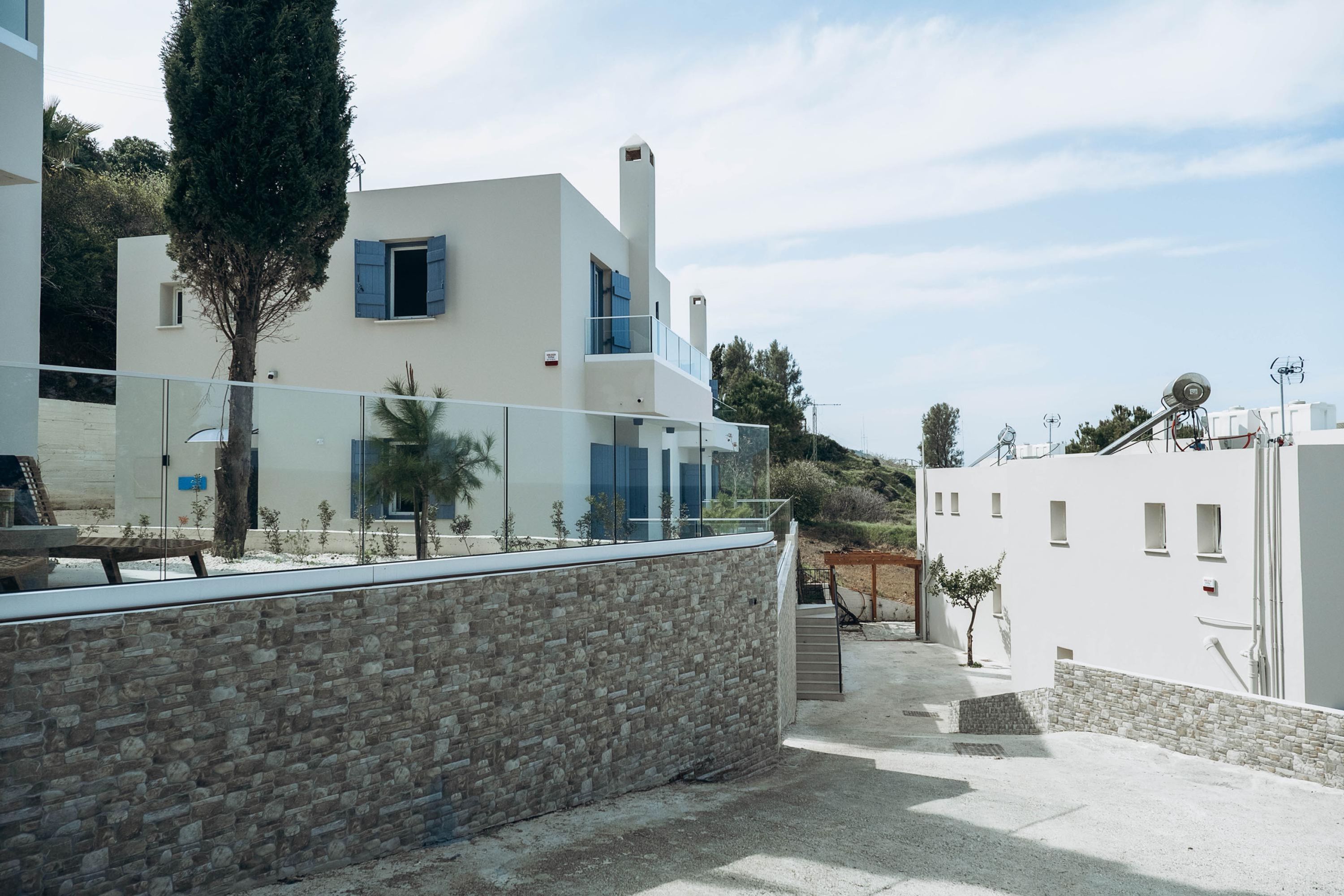 A modern building with a stone facade, a glass balcony, and a clear sky.