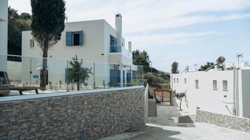 A modern building with a stone facade, a glass balcony, and a clear sky.