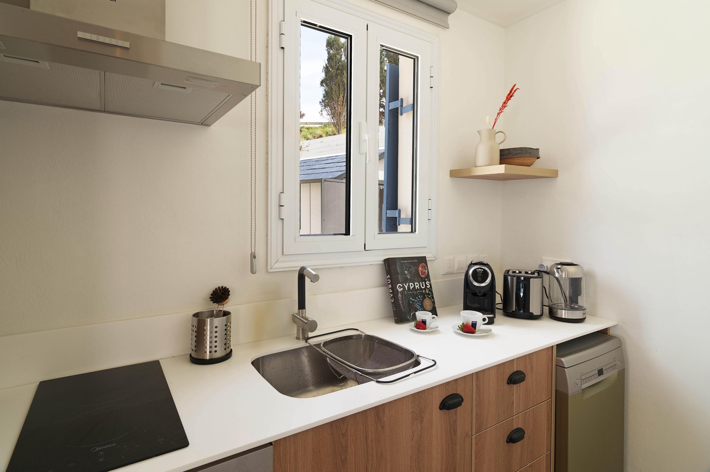 A modern kitchen with a built-in stove, a sink, and a window above the counter.