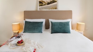 A neatly made bed with two pillows, a bedside table with a lamp, a book, and a bowl of strawberries. - Villa Paradise in Polis (Pachyammos)