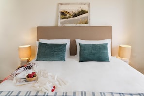 A neatly made bed with two pillows, a bedside table with a lamp, a book, and a bowl of strawberries. - Villa Paradise in Polis (Pachyammos)