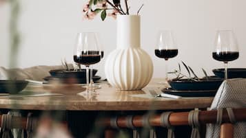 A dining table with a vase of flowers, wine glasses, and plates.
