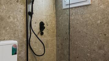 Un baño con inodoro, cabina de ducha y ventana.