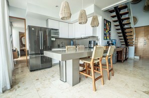 Eine moderne Küche mit einer zentralen Kochinsel, Edelstahlgeräten und einer Holztreppe.