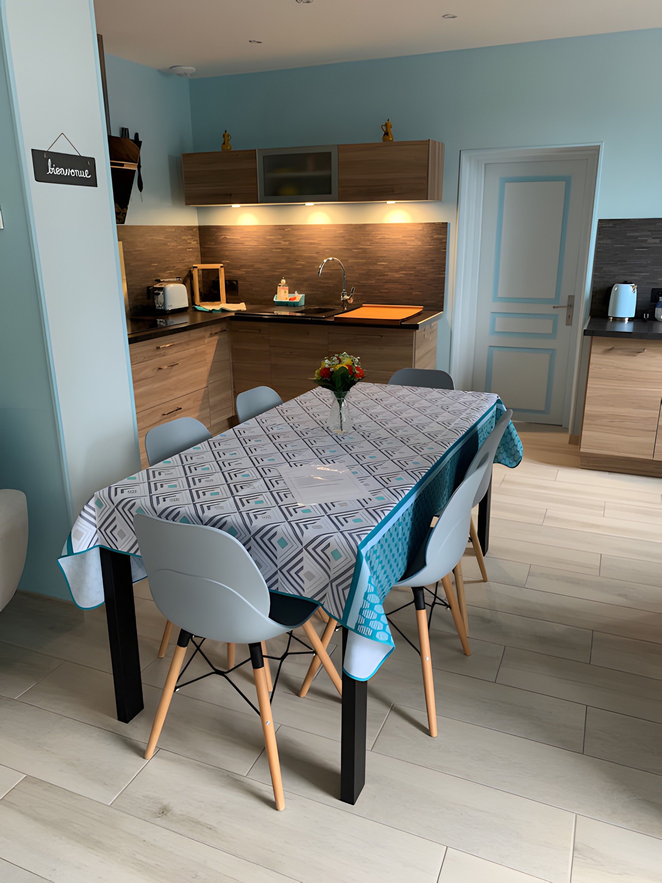 Una cocina moderna con armarios de madera, horno empotrado y comedor con mesa y sillas.