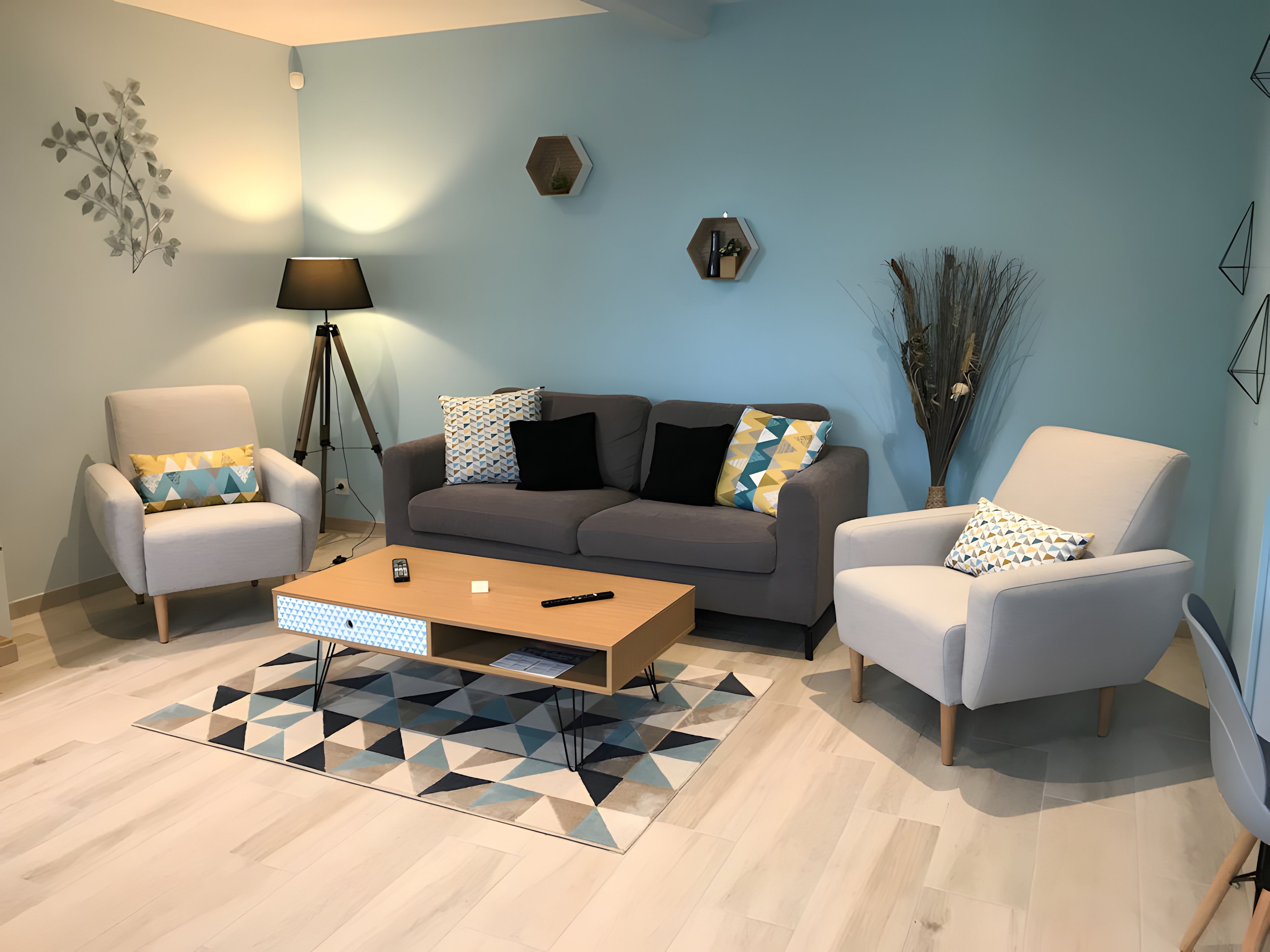 Een moderne woonkamer met een bank, twee fauteuils, een salontafel en een vloerlamp.