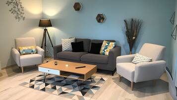 Een moderne woonkamer met een bank, twee fauteuils, een salontafel en een vloerlamp.
