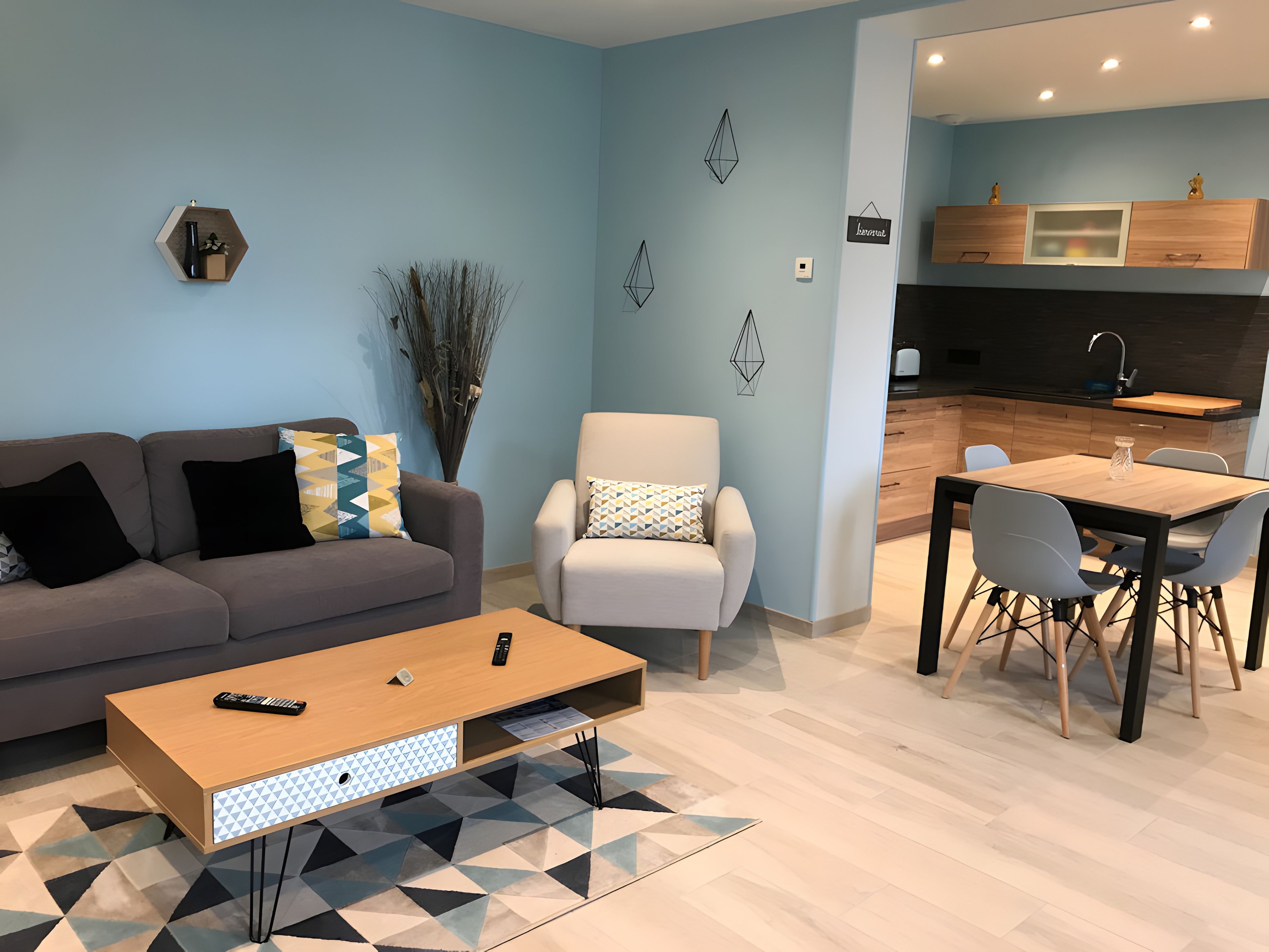 Een moderne woonkamer met een bank, fauteuil, salontafel en eethoek.