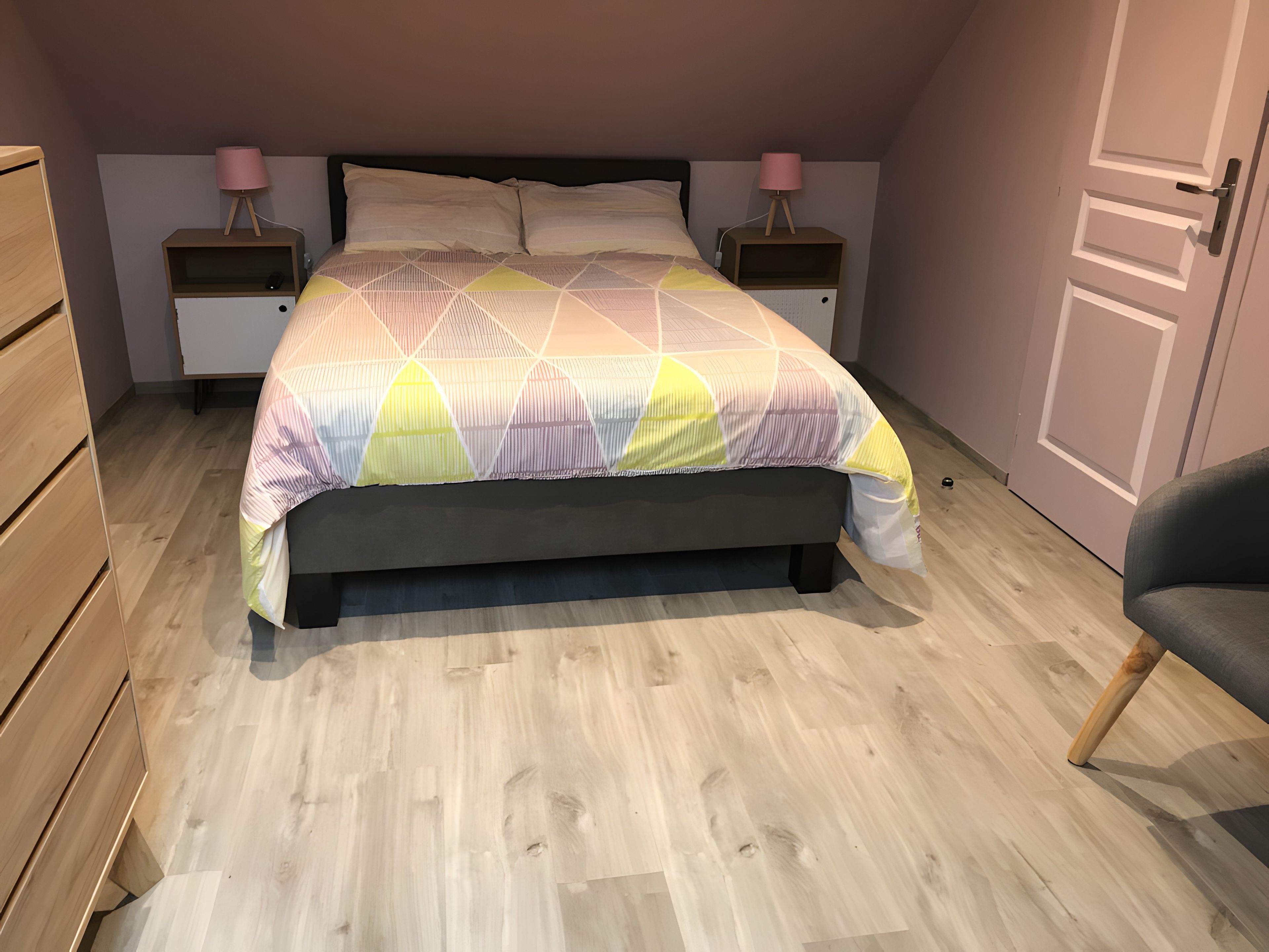 Een slaapkamer met een bed, twee nachtkastjes, een stoel en een kledingkast.