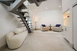 A modern interior with a staircase, two armchairs, a floor lamp, and built-in cabinets. - Casa de Malibu in Malibu (Malibu)