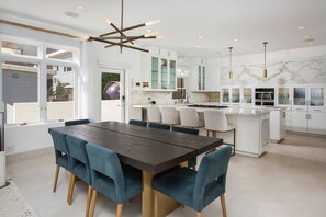 A modern kitchen with white cabinets, a marble backsplash, and a central island with seating. - Casa de Malibu in Malibu (Malibu)