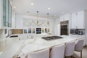 A modern kitchen with white cabinetry, a marble countertop, and stainless steel appliances. - Casa de Malibu in Malibu (Malibu)