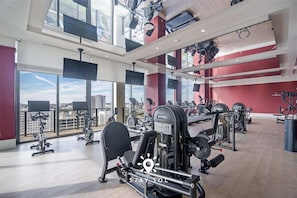 A gym with various exercise equipment, large windows, and a city view. - Stylish Miami Studio Perfect for City Living (Miami)
