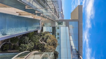 Um edifício moderno com fachada de vidro, piscina e céu claro.