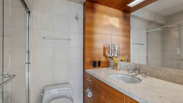 A modern bathroom with a large mirror, two sinks, and a toilet.