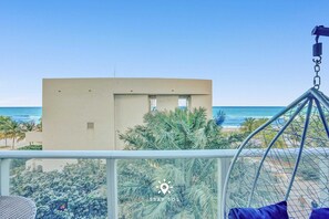 A view of a beach with a building in the background, a swing chair, and a logo with 'STAY SOL' text. - Cozy Apartment -balcony Beachfront Resort (Hollywood)