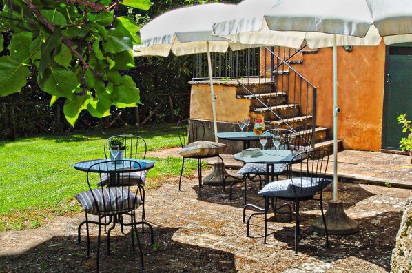 An outdoor patio with tables and chairs, a covered seating area, and a staircase leading to an upper level. - Montecasciano Oleandro (Capranica)