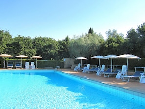 A swimming pool with lounge chairs and umbrellas.
