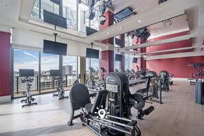 A gym with various exercise equipment, large windows, and a city view. - Downtown Studio Stylish Stay Spa Workspace (Miami)