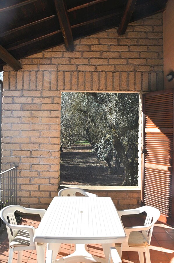 A patio with a brick wall, a table, and two chairs.
