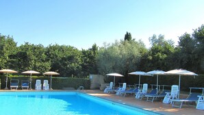 Una piscina con lettini e ombrelloni.
