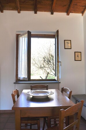A dining table with chairs, a window with curtains, and framed pictures on the wall.