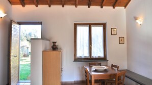 A dining area with a wooden table, chairs, a cabinet, and a window with curtains. - Montecasciano Mimosa (Capranica)