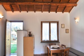 A dining area with a wooden table, chairs, a cabinet, and a window with curtains. - Montecasciano Mimosa (Capranica)