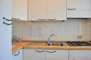 A kitchen with white cabinets, a stainless steel sink, a gas stove, and a wooden countertop.