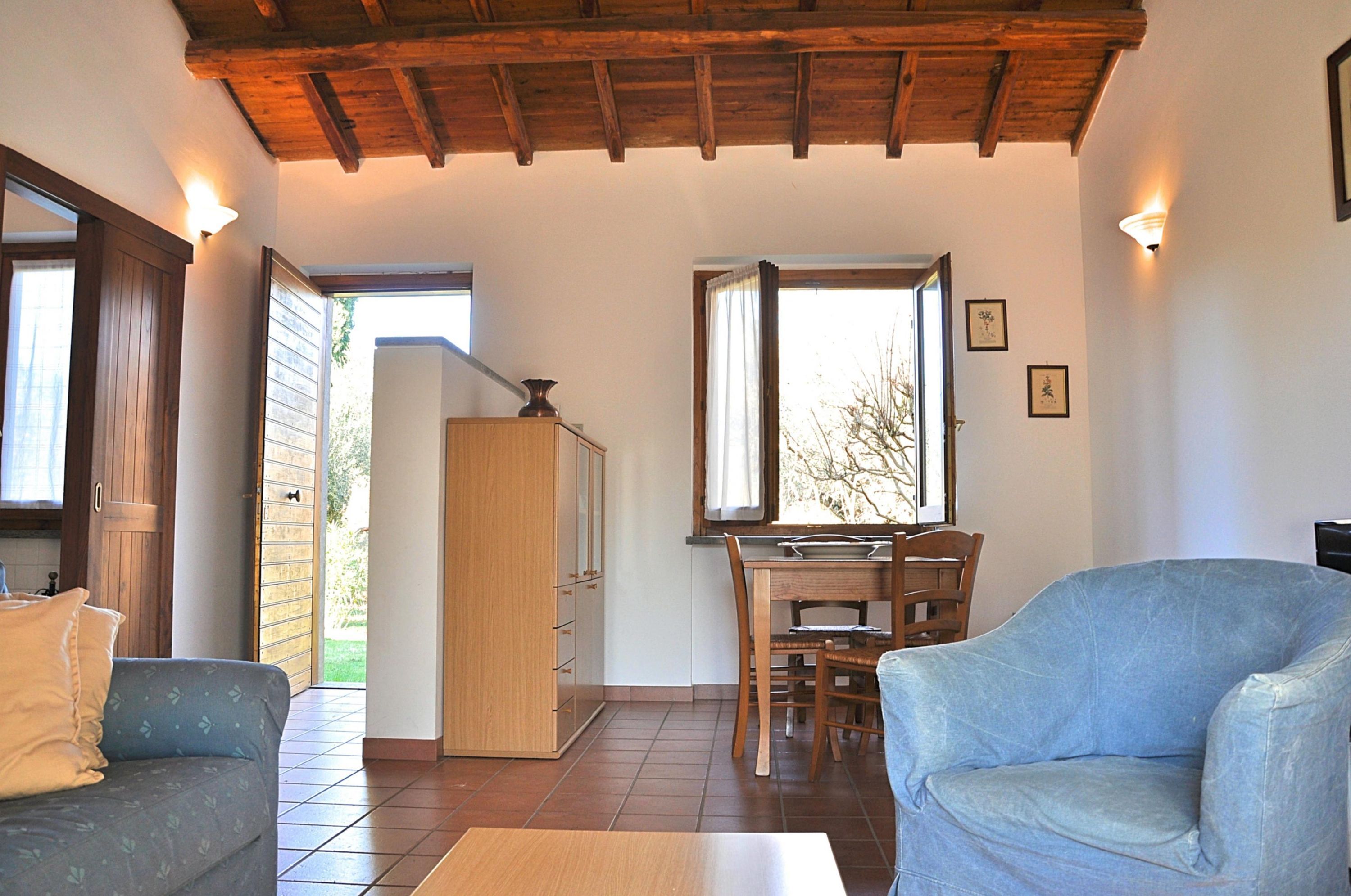 A room with a wooden ceiling, a dining table with chairs, a sofa, and a cabinet.
