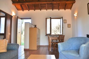 A room with a wooden ceiling, a dining table with chairs, a sofa, and a cabinet.